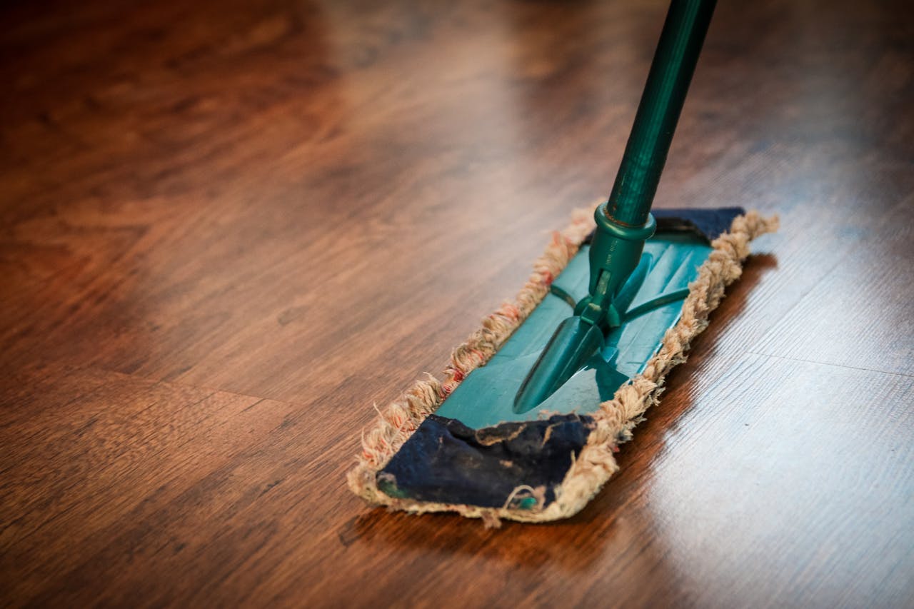 Services A detailed view of a mop cleaning a wooden floor, showing texture and pattern.
